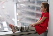 Данас променљиво облачно и нестабилно, могући пљускови Девојчица седи крај прозора. облачан дан