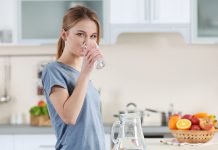 ПОПИЈЕТЕ ОВУ KОЛИЧИНУ ВОДЕ НА ПРАЗАН ЖЕЛУДАЦ ЧИМ УСТАНЕТЕ: Тако ћете најисправније ПРОЧИСТИТИ ОРГАНИЗАМ Млада жена пије воду из чаше у кухињи