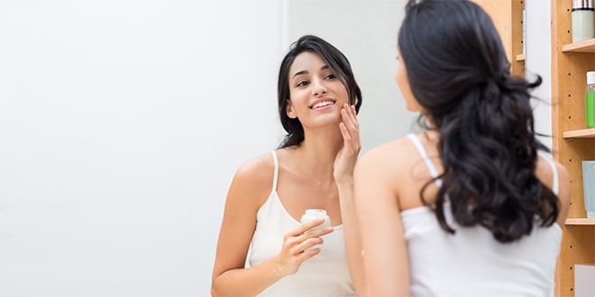 Млада жена наноси хидратантну крему на лице Млада жена наноси хидратантну крему на лице