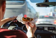 Загађење и лоша исхрана нам уништавају здравље Мушкарац вози аутомобил док једе хамбургер
