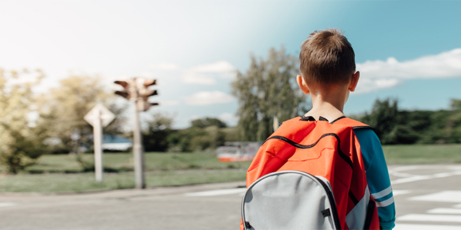 Школарац стоји и чека на прелазу зебре