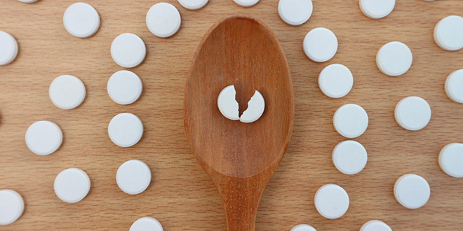 Таблета лека поломљена на пола на дрвеној кашици