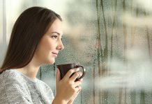 Данас облачно са падавинама, максимална дневна до 15 степени Жена стоји крај прозора и посматра кишовит дан