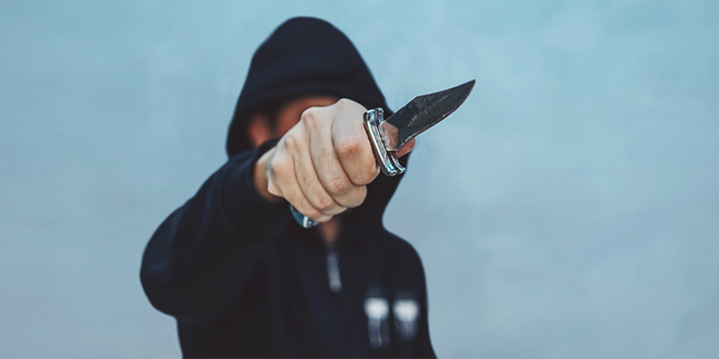 Мушкарац држи нож у руци и спрема се за напад