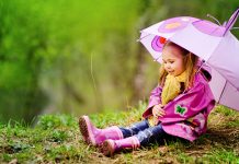 Данас претежно облачно, повремено са падавинама, максимална дневна температура око 18 степени Насмешена девојчица са кишобраном у кишном капуту седи на отвореном