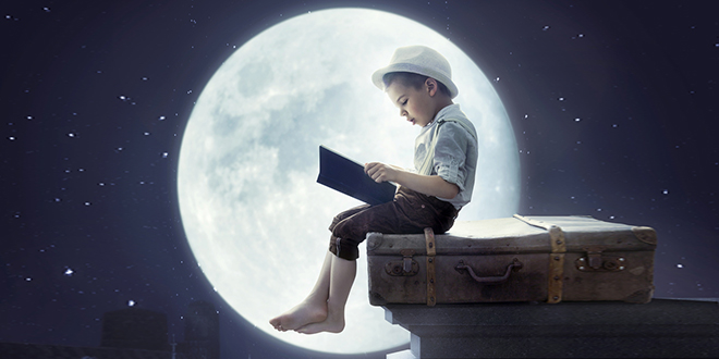 Дечак по месечини чита књигу на крову