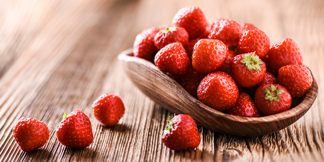 Јагоде у дрвеној чинији и на дрвеном столу