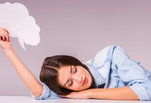 Треба ли да се забринете: Зашто људи причају у сну? Девојка спава на столу држећи у руци текстуални облачић