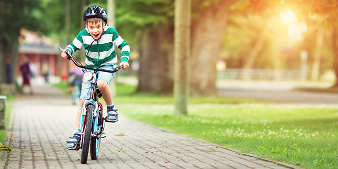 Дечак вози бицикл у парку