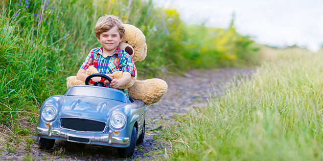 Dečak vozi plišanog medu u malom automobilu