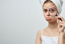 4 велике заблуде о бубуљицама и нези коже Тужна девојка показује под лупом своју бубуљицу на лицу