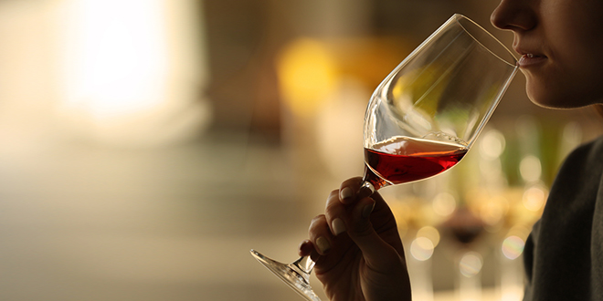 Жена пије црвено вино у стакленој чаши