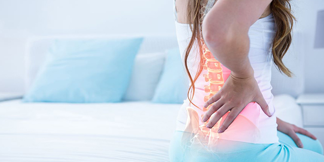 Девојка осећа бол у леђима Девојка осећа бол у леђима