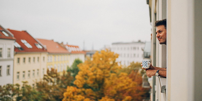 Мушкарац посматра град са прозора свог стана Мушкарац посматра град са прозора свог стана