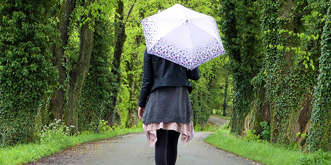 Девојка хода улицом и носи кишобран