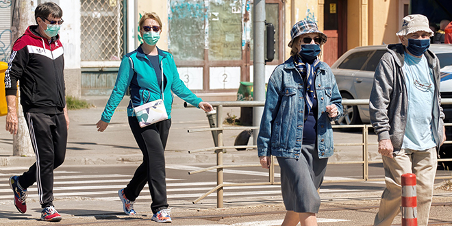 Људи на улици шетају са заштитним маскама на лицу Људи на улици шетају са заштитним маскама на лицу