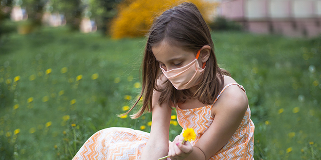 Девојчица бере цвеће са заштитном маском Девојчица бере цвеће са заштитном маском