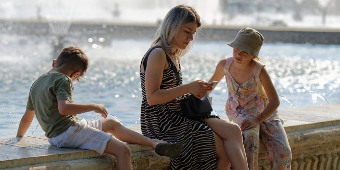 Жена седи са децом поред фонтане Жена седи са децом поред фонтане