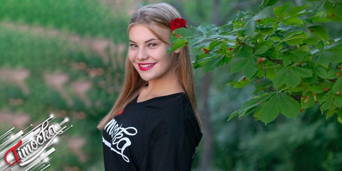 Девојка у мајици „Тимочка” стоји поред гране дрвета Девојка у мајици „Тимочка” стоји поред гране дрвета