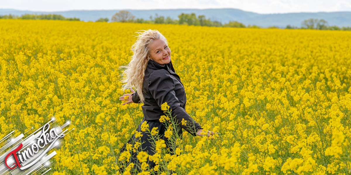 Жена са плавом косом у пољу цвећа